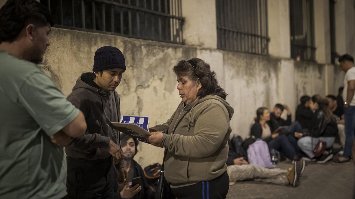 Idaleque revisa la lista de las personas que esperan en la fila, un sistema de autoorganización para evitar problemas durante la noche de espera frente a los servicios sociales