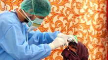 Un trabajador de la salud con equipo de protección completa recoge una muestra de un residente en un centro de pruebas de coronavirus.