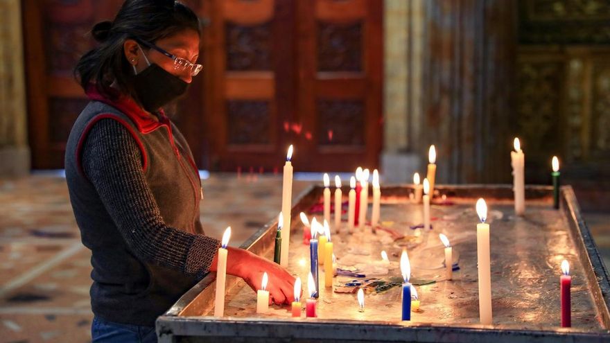 Una ecuatoriana con mascarilla enciende velas este jueves, en la iglesia de Santo Domingo, en Quito (Ecuador). El porcentaje de positivos de coronavirus en Quito ha crecido en un mes tres puntos porcentuales, según las pruebas realizadas por el Municipio, que trata de controlar el avance de contagios en los mercados y barrios del sur de la ciudad para evitar el colapso del sistema sanitario.