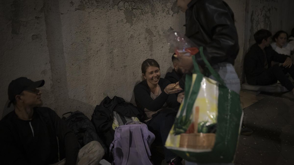 Una mujer llega con bollos y café, y lo reparte entre todos los integrantes de la fila frente a los servicios sociales.