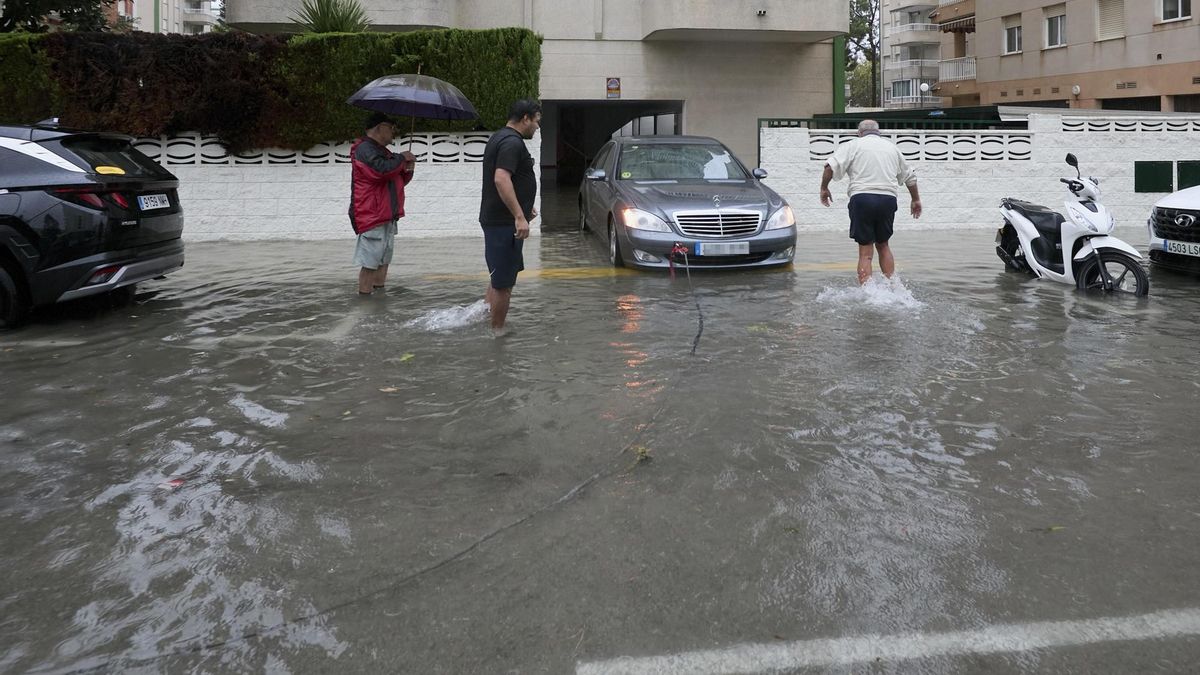 Residentes de Gandía ayudan a un vecino a sacar su vehículo de un garaje inundado este lunes.