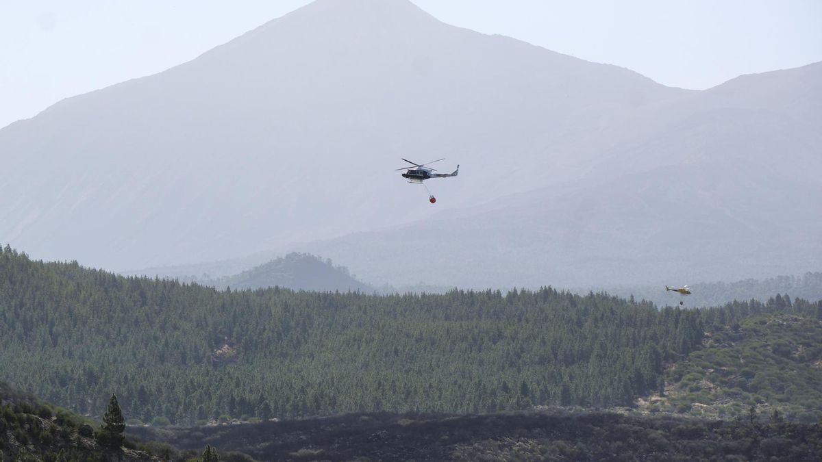 En la imagen, dos helicópteros sobrevuelan la zona afectada del incendio en Tenerife, con el Teide al fondo.