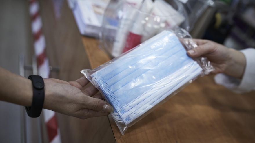 Una farmacéutica enseña un paquete de mascarillas