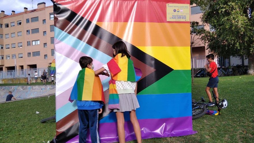 Dos niños, junto a una pancarta con la bandera LGTBI