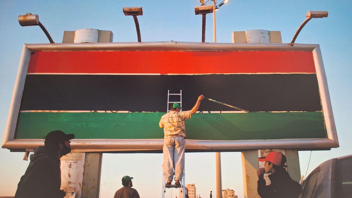 Bernat Armangué inmortaliza a un libio pintando sobre un cartel publicitario la bandera de antes de la irrupción de Gadafi