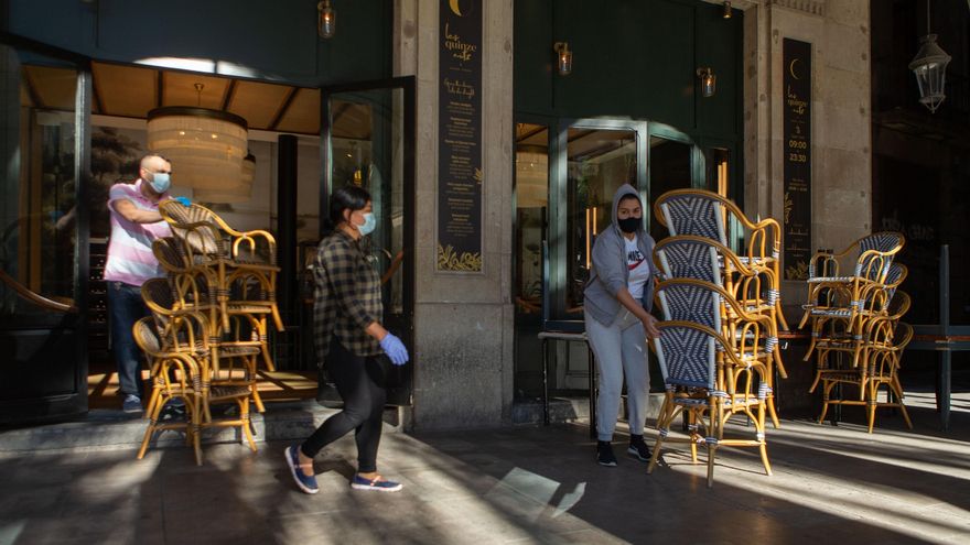 Dos trabajadores recogen la terraza de un bar del centro de Barcelona. EFE/Enric Fontcuberta/Archivo