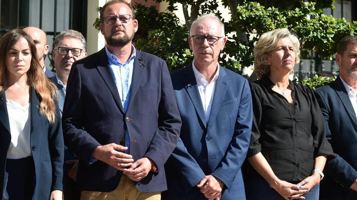 El exconcejal de Urbanismo de Murcia Andrés Guerrero, del PSOE, en segunda fila por la izquierda, con gafas; y el actual teniente de alcalde de Urbanismo, Antonio Navarro, del PP, tercero por la derecha, durante el minuto de silencio por las víctimas