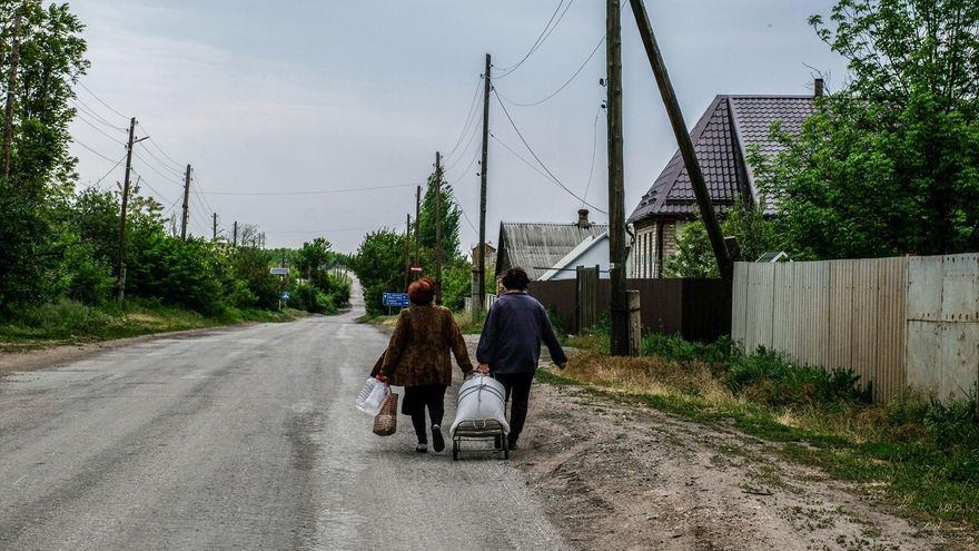 Dos mujeres caminan por una carretera cercana a Severodonetsk para rellenar sus botellas de agua