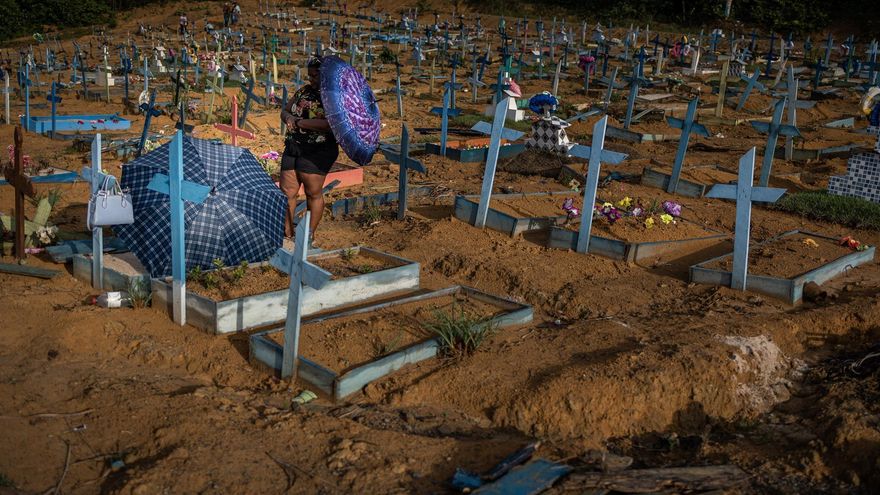 Personas se protegen del sol mientras visitan las tumbas de familiares en el área destinada a las víctimas de COVID-19 en el cementerio Nossa Senhora Aparecida, en Manaos.