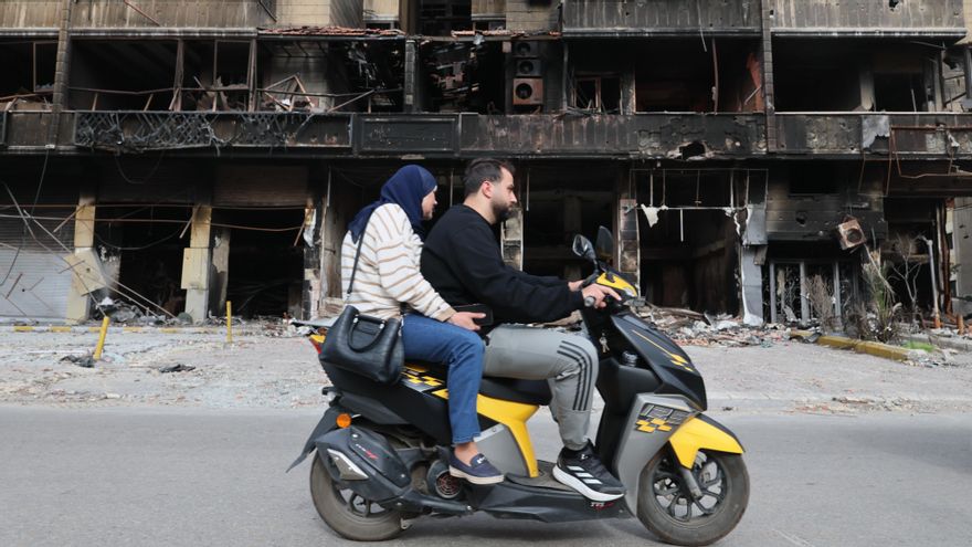 Varias personas pasan en coche junto a edificios dañados en los suburbios del sur de Beirut, Líbano, este viernes.