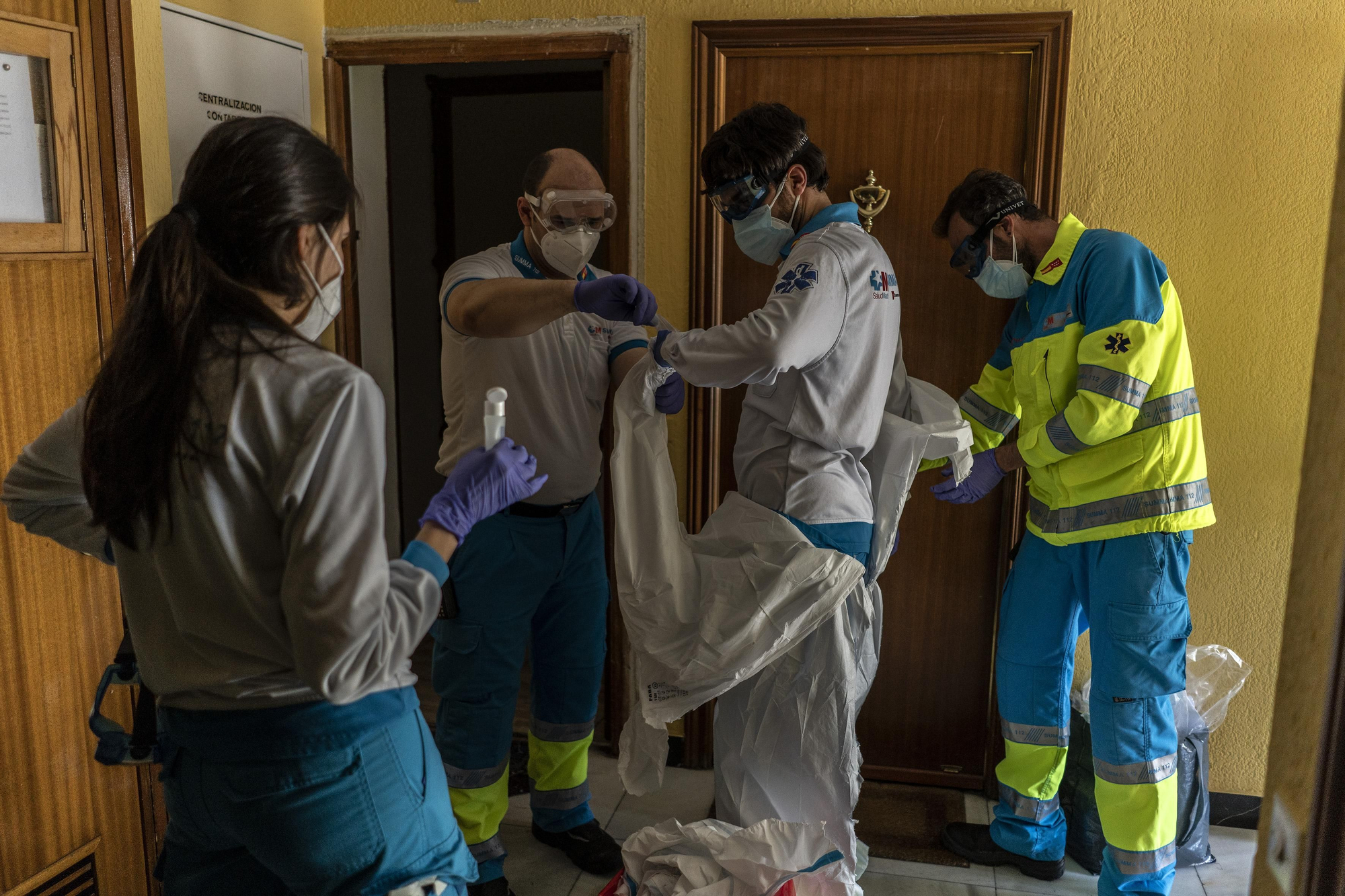 Carlos Rubio, médico, se quita el EPI, con ayuda de Ana Moreno, enfermera, Ignacio Crespo y José Sevillano, técnicos en emergencias, después de visitar a Fabio en su casa, con síntomas de tener el COVID-19. Los protocolos de desinfección son muy estrictos en este tipo de emergencias.