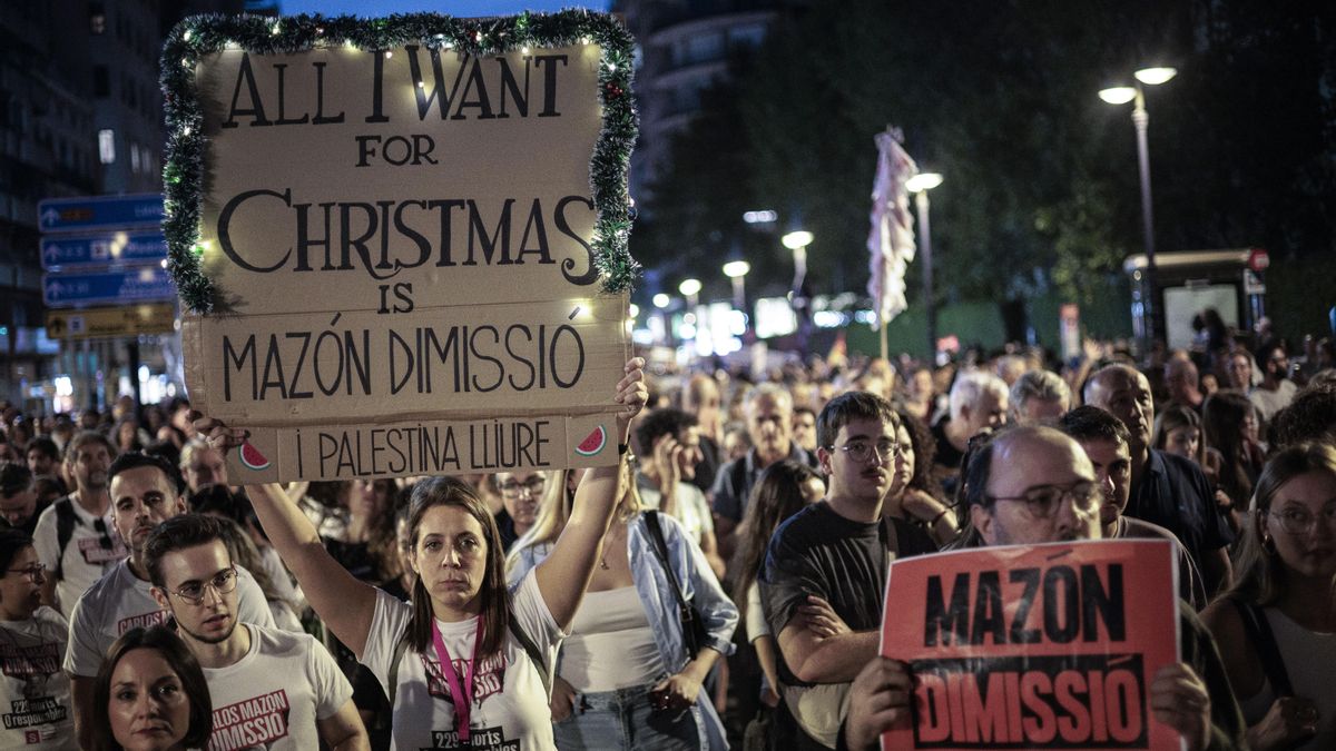 Una mujer con un cártel de "Lo que quiero por Navidad es la dimisión por Mazón" durante la manifestación
