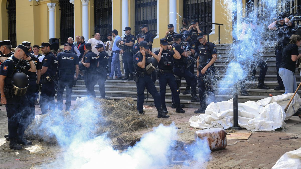 Varios policías se tapan los oídos después de que los ganaderos lanzaranpetardos durante la movilización ante la sede de Presidencia del Gobierno de Asturias, en Oviedo/Uviéu.