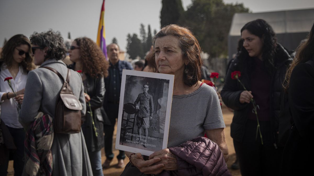 Una mujer con la foto de un familiar desaparecido en el acto de cierre de la fosa de Pico Reja (Sevilla).