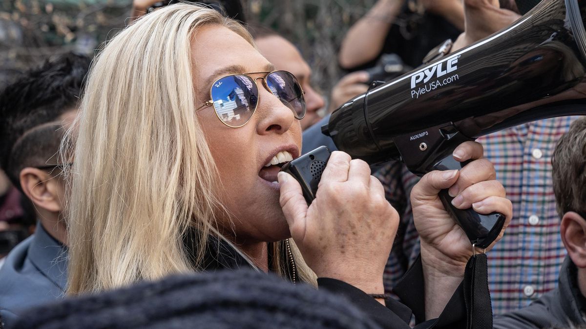 A congressista Marjorie Taylor Greene com um megafone em frente ao tribunal de Nova York que julgava Trump por pagamentos à atriz pornô Stormy Daniels.