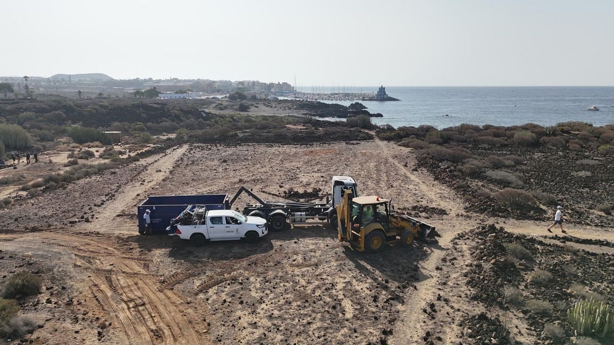 Retirada de los residuos en la playa Los Enojados, en Arona, con el puerto deportivo de Las Galletas al fondo.