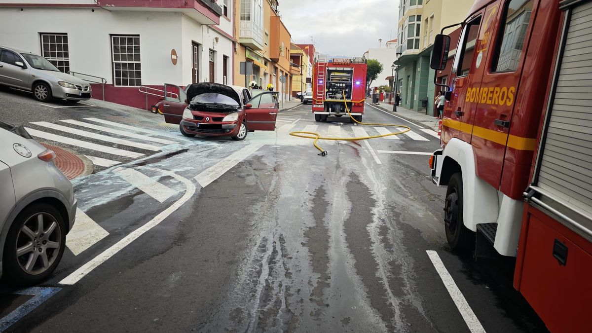 El vehículo afectado por un incendio y Bomberos La Palma en la Calle Treinta de Mayo de Breña Alta en la mañana de este lunes, 16 de junio.