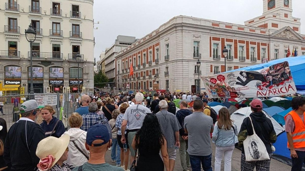 Un guía orienta con un banderín a un grupo de turistas junto a la acampada de Sol.