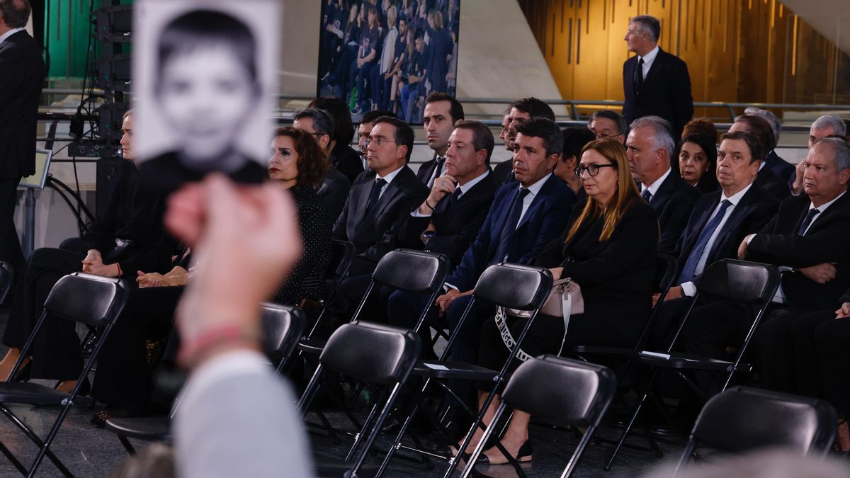 Un familiar levanta el retrato de una de las víctimas de la dana ante un grupo de representantes políticos entre los que está Carlos Mazón