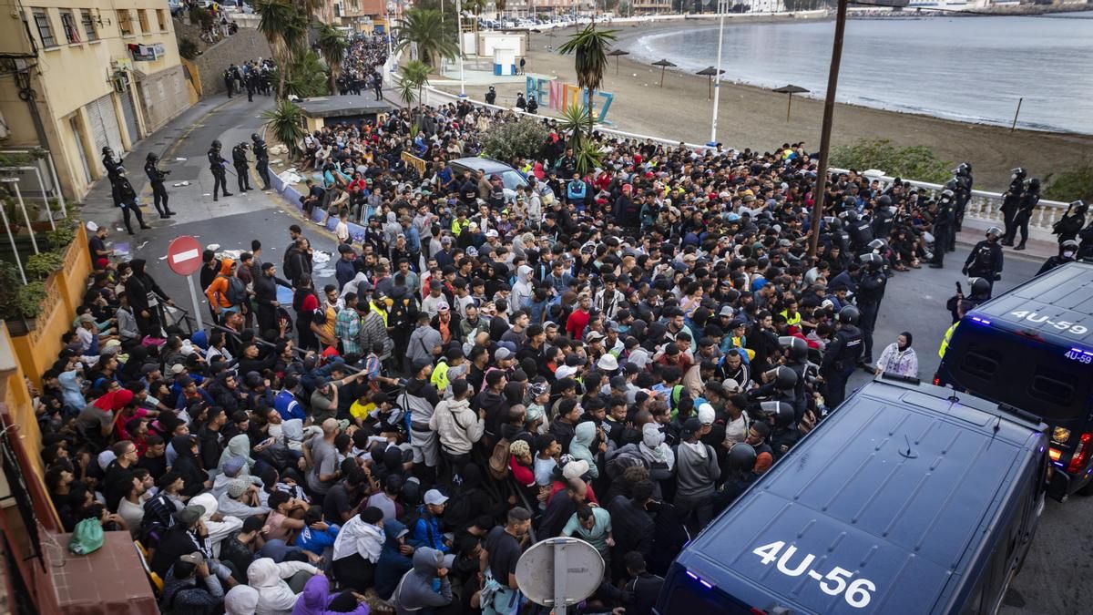 La multitud de personas se apelotona ante la línea policial junto a la playa de Benítez antes de emprender el camino al puerto.