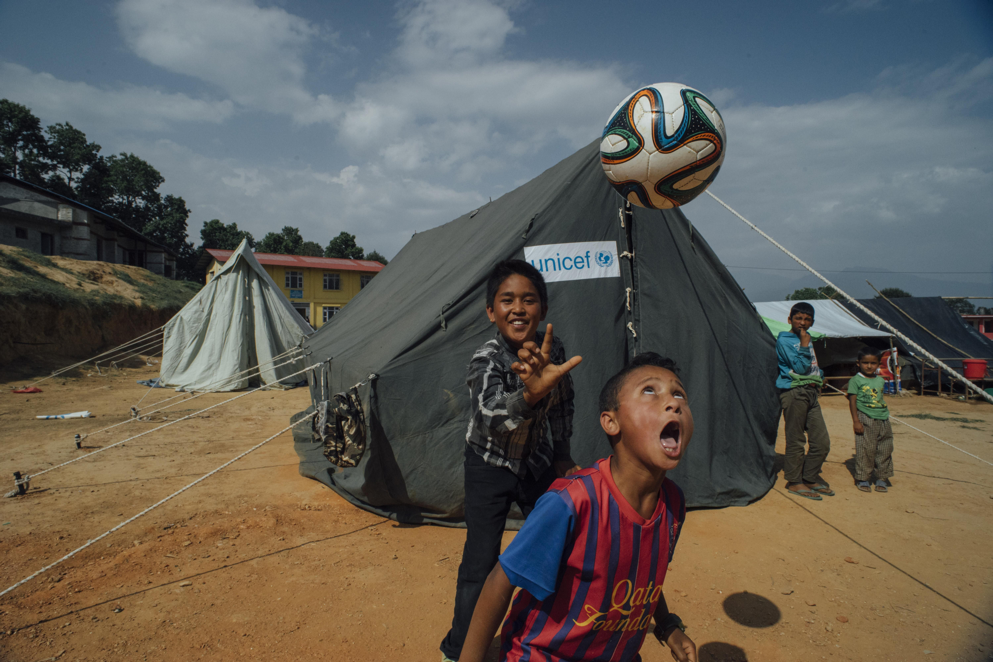 Niños juegan al fútbol en uno de los puestos “Amigos de la infancia” de Unicef, en un campo para desplazados por el terremoto en eldistrito de Dolkha, epicentro del terremoto de 12 de mayo. Según la organización, cerca de un millón de niños afectados por los seísmos de abril y mayo siguen viviendo en zonas en las que hay un alto riesgo de deslizamientos de tierra e inundaciones. Foto: Brian Sokol/ Unicef.