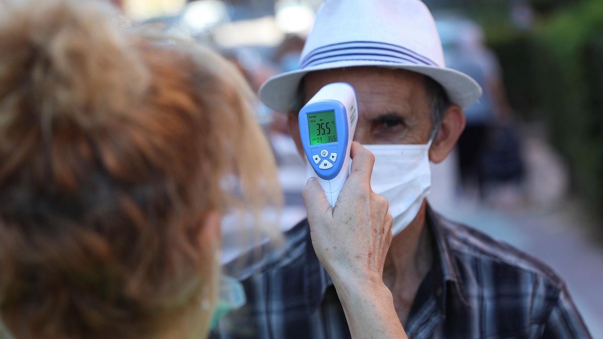 Una voluntaria de una asociación de mayores toma la temperatura a un anciano