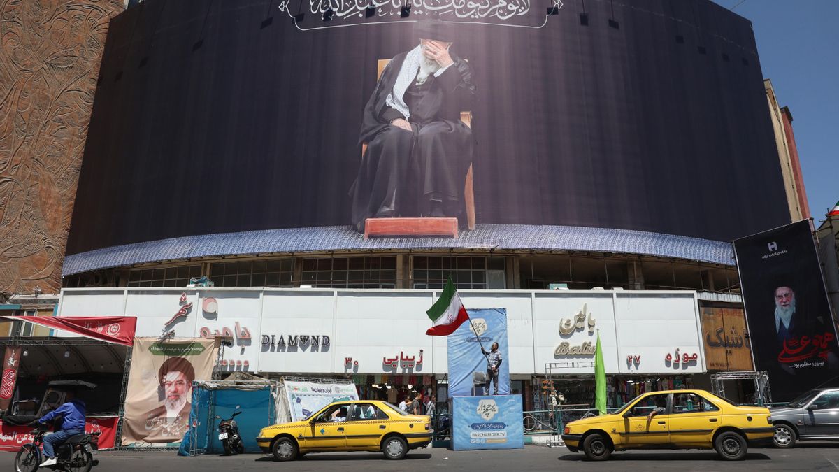 Un iraní sostiene la bandera nacional de Irán junto a una valla publicitaria con el difunto líder supremo iraní, el ayatolá Alí Jamenei, en la plaza Valiasr de Teherán, Irán, el 15 de junio de 2026. EFE/EPA/ABEDIN TAHERKENAREH
