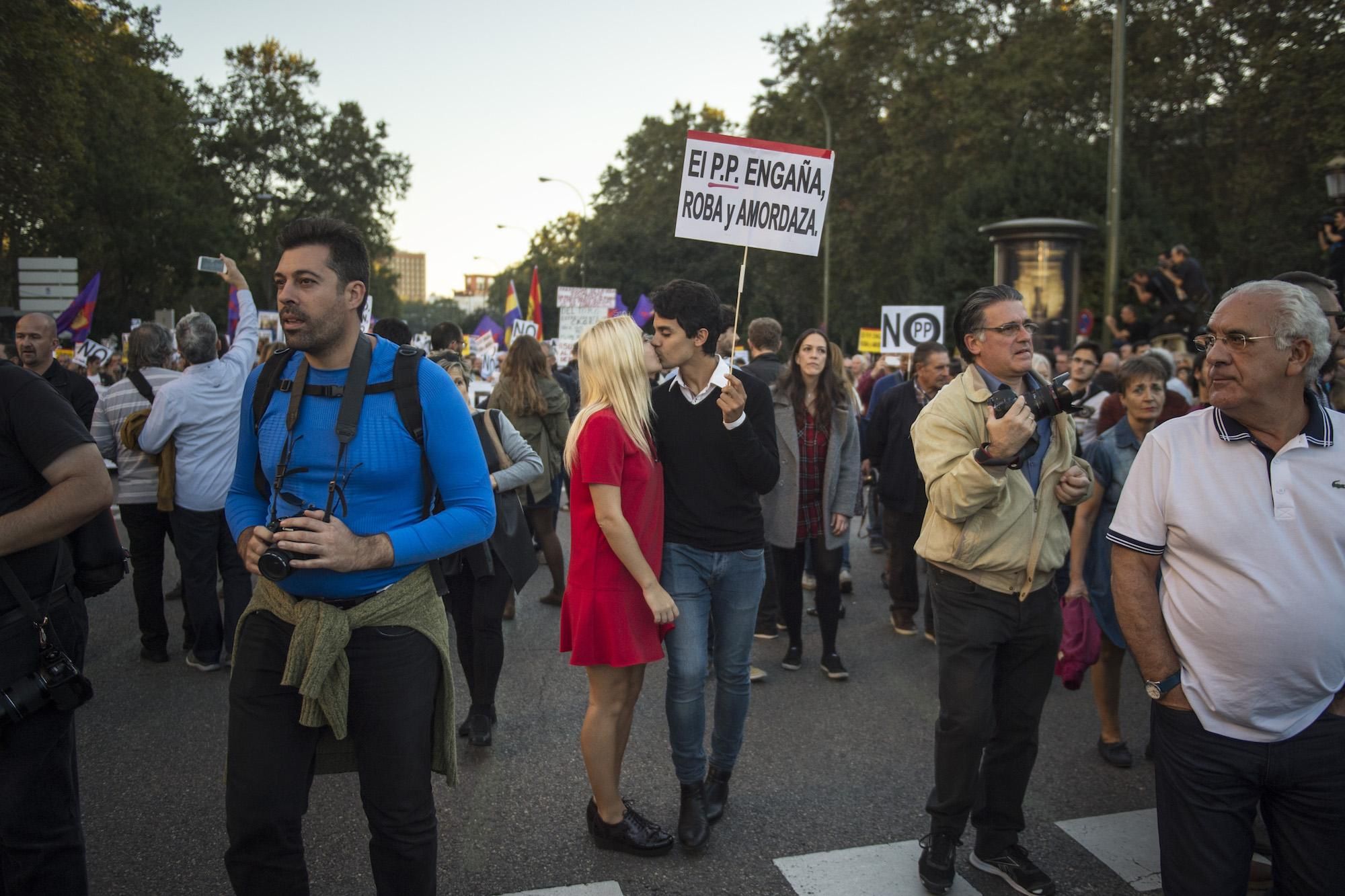 Dos manifestantes se besan bajo una pancarta crítica con el Partido Popular: "El PP engaña, roba y amordaza"
