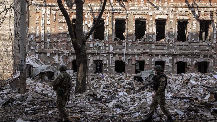 Dos militares ucranianos caminan sobre los escombros causados por los bombardeos rusos en Járkov.
