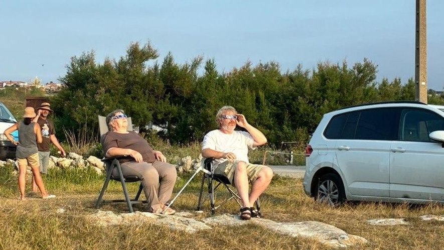 Una pareja observa el eclipse en uno de los ‘praos’  del entorno de la playa de El Bocal, en la costa norte de Santander, segundos antes de nublarse.