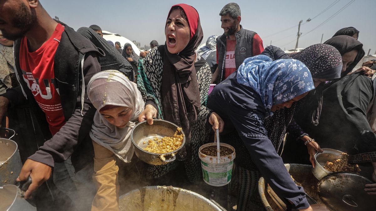 Palestinos desplazados se reúnen para recibir una porción de comida en el campo de refugiados de Jabalia, al norte de la Franja de Gaza.