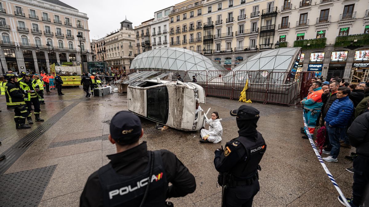 Dos agentes de Policía Nacional delante de una activista de Greepeace con un vehículo, tras realizar una acción en la Puerta del Sol