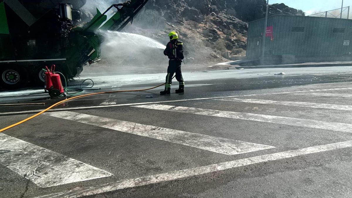 Un bombero refresca la maquinaria afectada en el incendio originado este viernes por la tarde en el vertedero de Juan Grande.