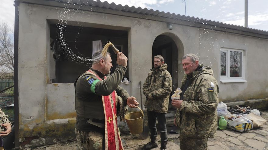 Un sacerdote castrense bendice con agua a dos soldados en un área cercana a la ciudad de Izium, en la región de Járkov.