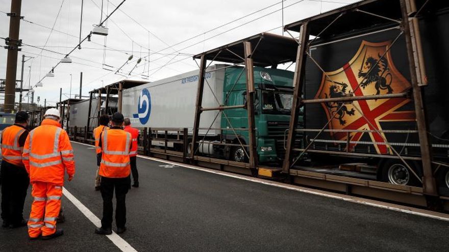 Varios operarios supervisan el paso de un convoy de camiones en las instalaciones del Eurotúnel de la localidad inglesa de Folkestone, en el condado de Kent, en el lado británico de esta monumental obra, que este año celebra su 25 aniversario marcado por los desafíos que presenta el Brexit.