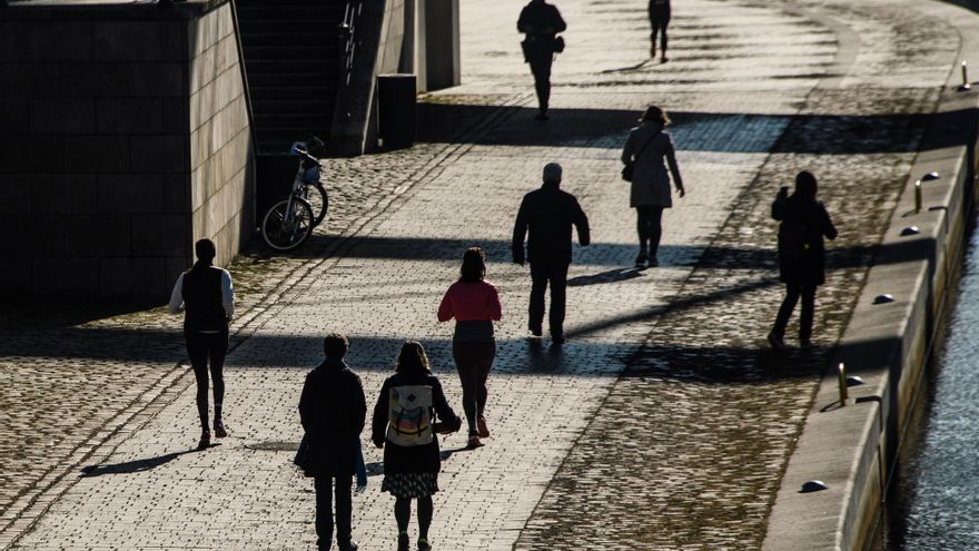 Varias personas pasean por la orilla del río Spree frente al parlamento alemán 'Bundestag', en Berlín, Alemania. EFE/ Clemens Bilan