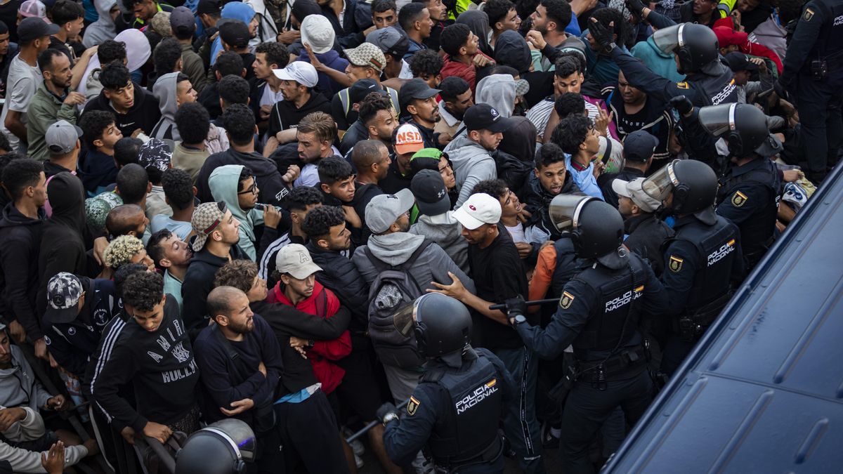Decenas de migrantes durante el comienzo del traslado al campamento del puerto de Ceuta.