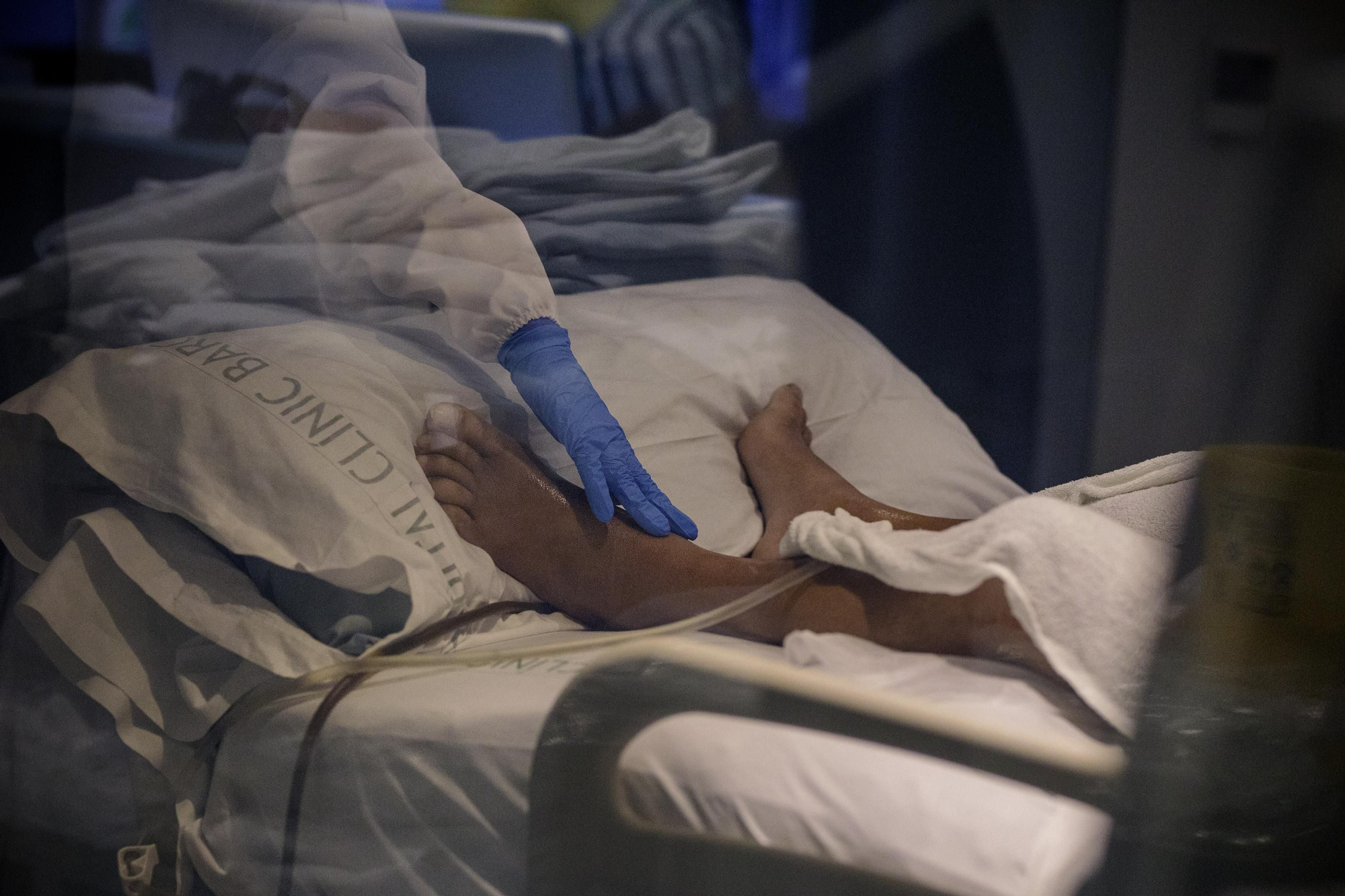 Una enfermera acaricia el pie de un paciente que presenta una fiebre muy alta y graves complicaciones respiratorias provocadas por el coronavirus SARS-CoV-2. Uno de cada tres pacientes hospitalizados en España presentan el Síndrome de Distrés Respiratorio Agudo.