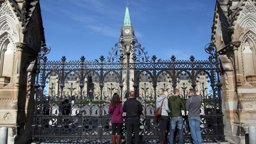 Personas miran el Parlamento desde fuera de las puertas principales en Ottawa, Canadá, en una fotografía de archivo. EFE/EPA/Cole Burston