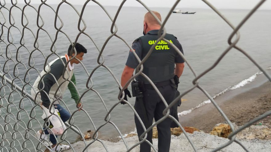 Un Guardia Civil ayuda a uno de los inmigrantes en uno de los espigones fronterizos de Ceuta este martes. EFE/Reduan