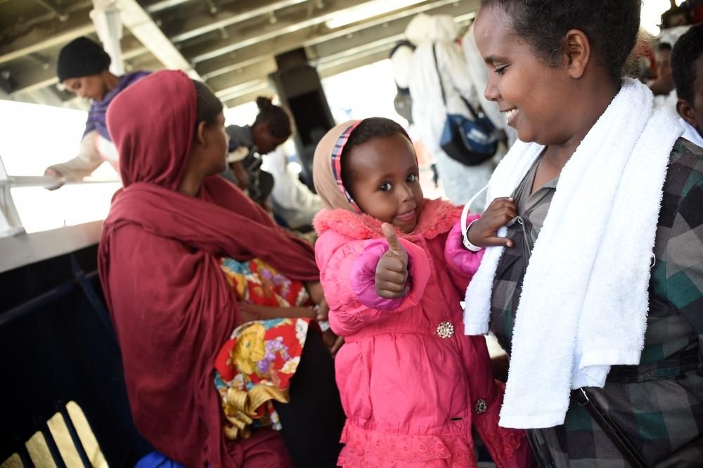 La pequeña Nitan, de apenas 2 años y medio, celebra junto a su madre la cercanía de la costa. Fueron rescatadas junto a otras 367 personas, entre ellas 66 mujeres 8 de ellas embarazadas y 45 menores. Como Nitan y su madre, la mayoría procedían de Eritrea. Fotografía: Ikram N'gadi/MSF