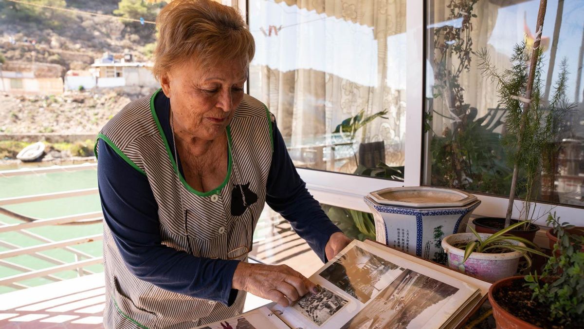 Ana María Ortega, que vive en su barraca de la Algameca Chica desde hace 75 años, con un álbum de fotos antiguas de la vida en el asentamiento, señala una fotografía de su familia, en los años 60