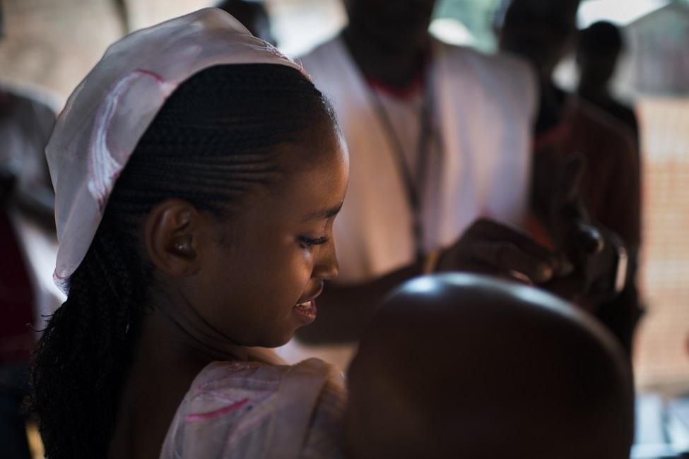 La madre de Madina, de 12 meses de edad, lleva al menor al centro de vacunación junto a su madre.