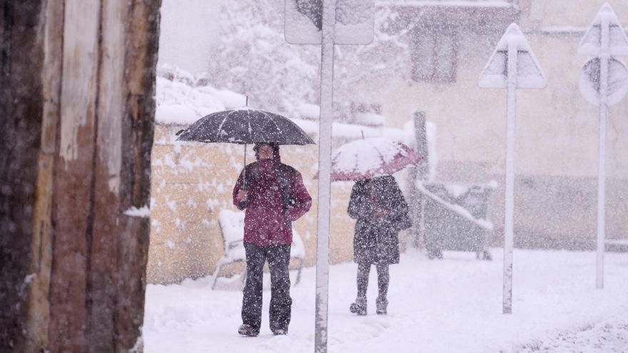 Dos personas caminan por una calle cubierta de nieve.