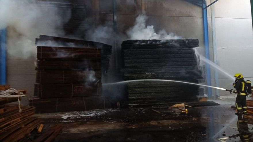 Los bomberos trabajan para apagar un incendio declarado en una nave industrial de maderas en Arinaga