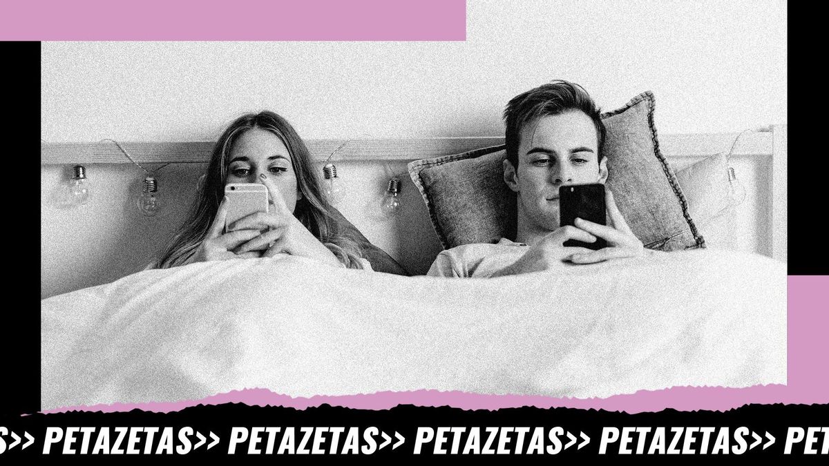 Imagen de archivo de una pareja utilizando el teléfono móvil en su cama