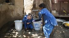 Dos refugiados afganos de tercera generación juegan en un pozo de agua, el pasado 4 de julio en el campo de Kababian, en el noroeste de Pakistán | FOTO: EFE