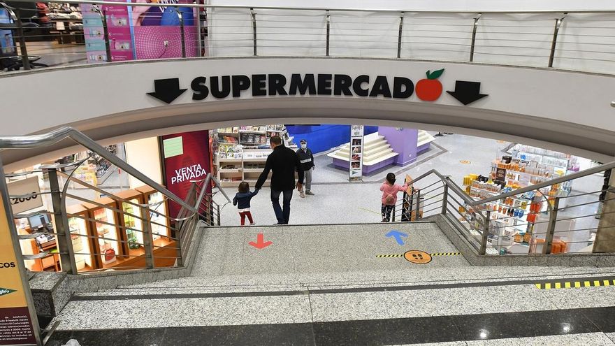 Varias personas realizan sus compras en un centro comercial.