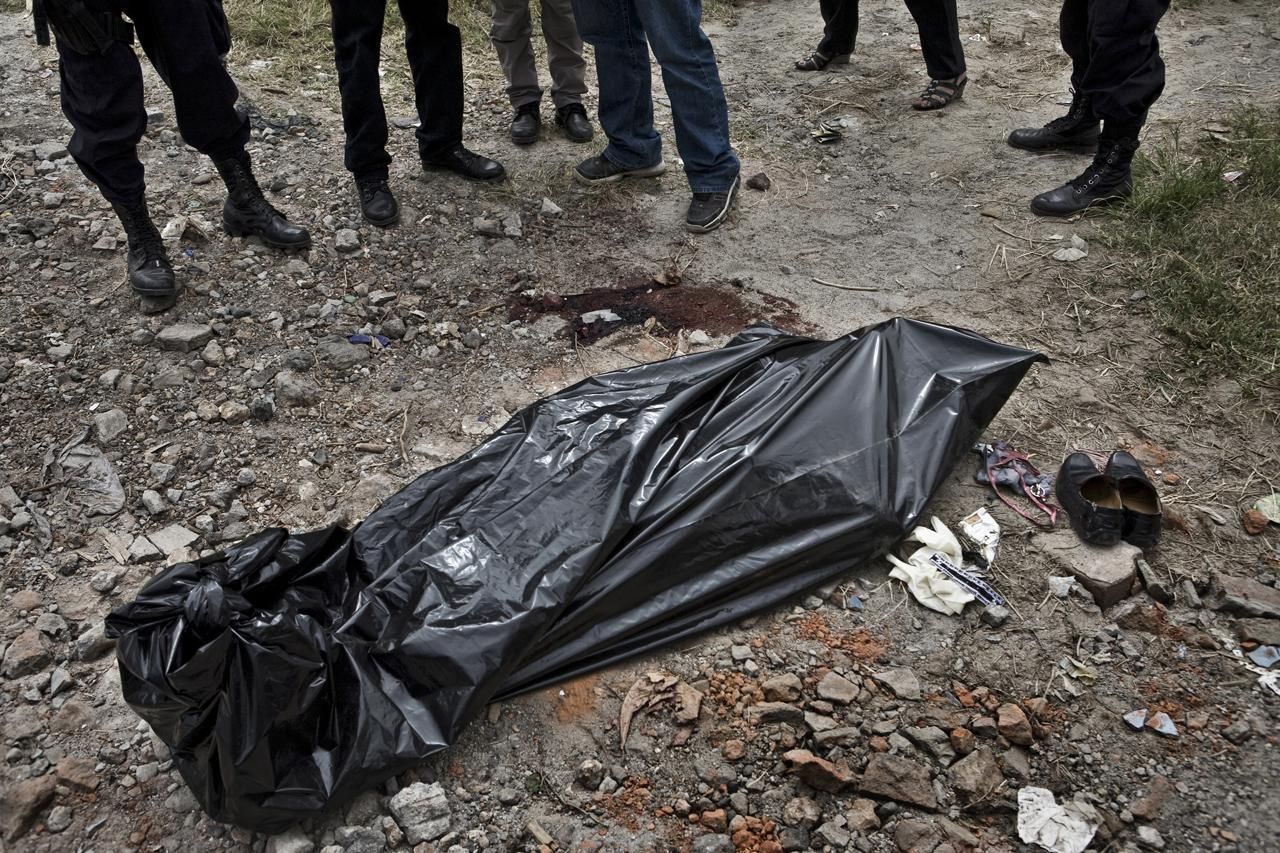 El doctor Abullarade, polícias de laboratorio criminalístico y un fiscal, hablan cerca del cadáver de un joven en Mexicanos, un municipio cercano a San Salvador./Edu Ponces (RUIDO Photo)