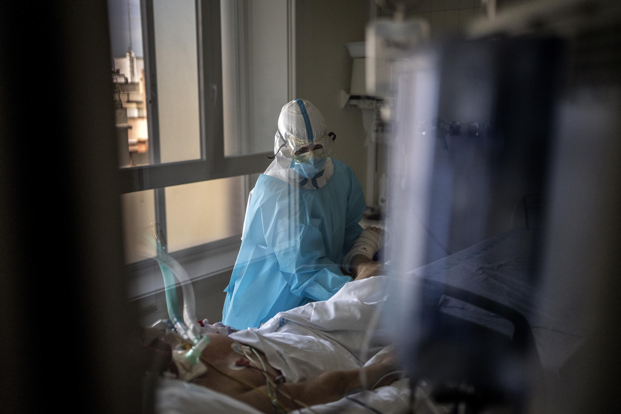 Una fisioterapeuta trata a un paciente con COVID-19 en la UCI del hospital. Los pacientes que pasan muchas semanas ingresados necesitan que les ejerciten las articulaciones.